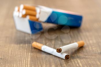 Two cigarettes lying near the box full of cigarettes