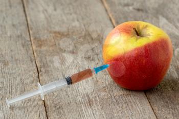 Syringe and apple. Concept for genetically modified food and cosmetic medicine