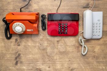 Three old telephones on wooden background. Top view,copy space.