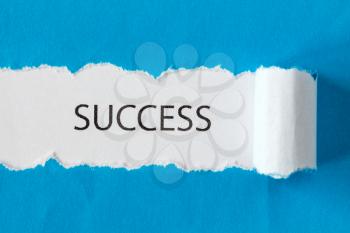 The word SUCCESS appearing behind torn blue paper