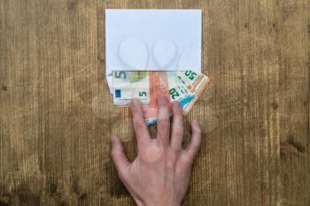 Hand takes an envelope with money, bills, Euros, payment. Shadow economy, illegal salary in an envelope without taxes.