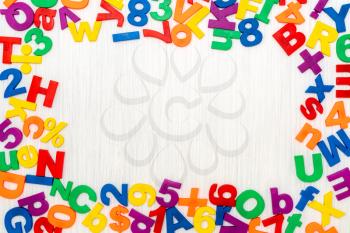 Colorful plastic numbers and letters as frame on a wooden background