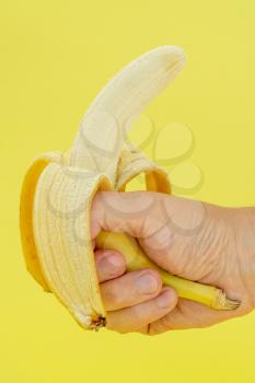 Human hand holding banana on yellow background. Nutrition Concept