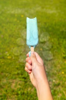 Child holding melting ice cream on summer nature background