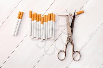 Cutting cigarettes by scissors. Anti smoking or quit smoking concept.