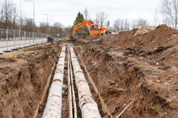 Repair of city communications. An orange excavator dug a trench for renew old pipes