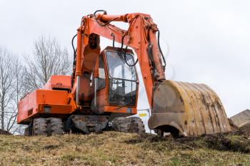 Close up details of orange excavator working on construction site