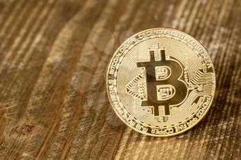 One golden bitcoin on wooden background