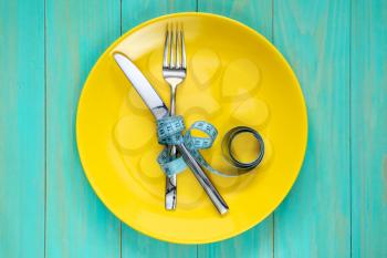 The concept of starvation or diet. Plate with knife, fork and measure tape