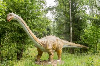 Statue of realistic dinosaur in a wild forest