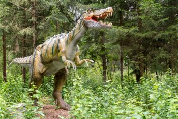 Statue of realistic prehistoric dinosaur in a wild forest