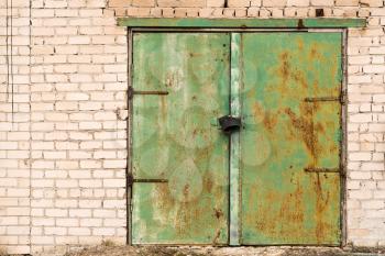 Green rusted metal door on brick wall