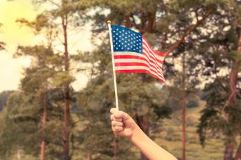 Kid holding small US flag on the wind outdoor