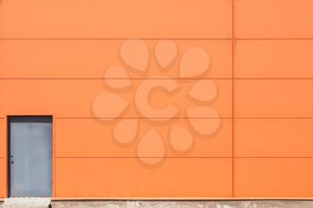 Modern orange building wall with metal doors