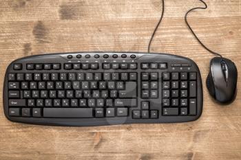 Black computer mouse and keyboard on the wooden desk