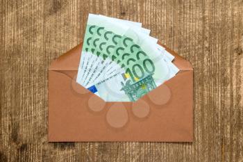 Brown envelope with Euro currency over wooden background