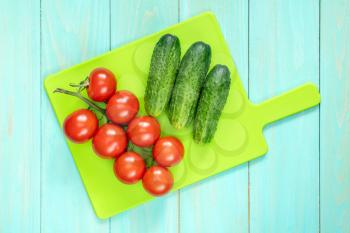 Fresh tomatoes and cucumbers on cutting board