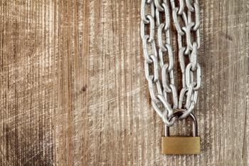 Padlock with chains on the old wooden background