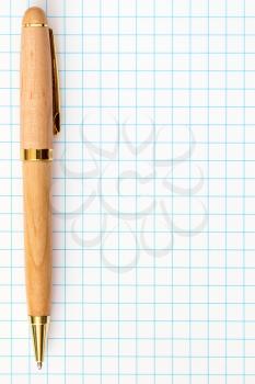 Wooden ball pen on squared paper background