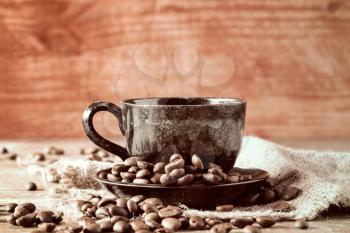 Coffee cup and roasted coffee beans on piece of sackcloth