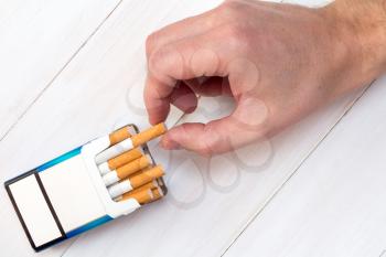 Smoking concept. Hand takes a cigarette out of pack.