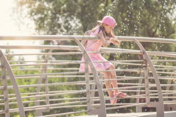 Cute little girl standing on a metal bridge