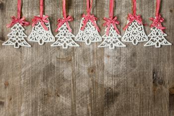 Decorations shaped as christmas tree and bell hanging over wooden background