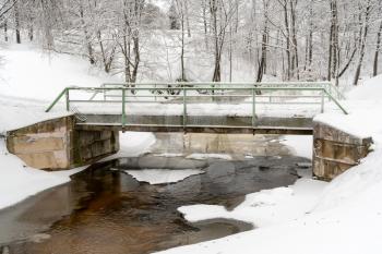 Small bridge over winter river in the park