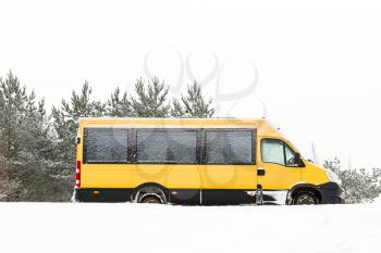School bus covered with fresh snow. Minibus under the snow. Sleet slush, ice covering on the roads.