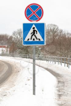 Pedestrian crossing road sign with snow. Drive safely in winter time.