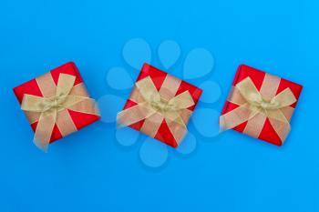 Three Gift boxes with golden bows on blue background. Top view.
