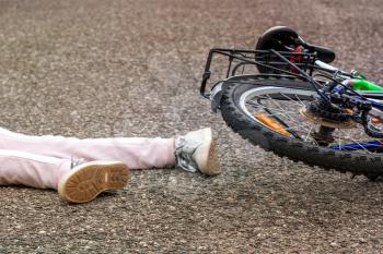 Bicycle accident concept. Girl fallen off her bicycle outdoors.