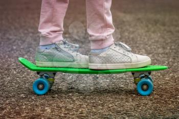 Closeup of skateboarder legs. Girl ride skateboard on a city street.