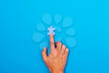 Concept of business. Hand pointing at pieces of puzzle ower a blue background