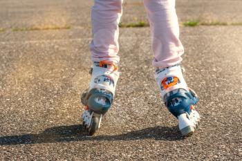 Little girl on roller skates ride on the road 