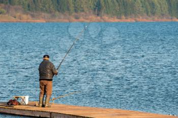Unrecognizable rear view of senior man fishing on the lake