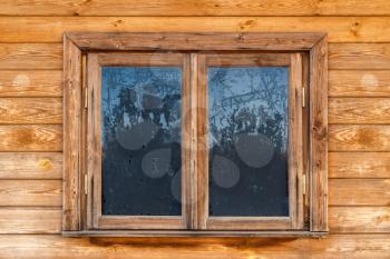 Frozen window of country log house in a village on winter