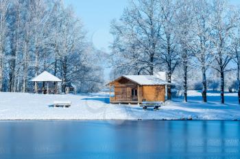 Ecological summerhouse near the frozen lake in the early winter