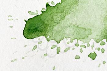 Splatter of green watercolor on a white paper