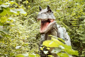 Statue of Gorgosaurus dinosaur in a green forest