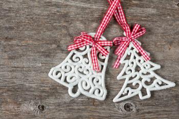 Decorations shaped as fir tree and bell over wooden background