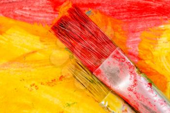 Red and yellow watercolor brushes on abstract colorful painting
