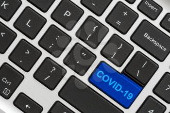Blue key on a black computer keyboard with text - Covid-19 Coronavirus. Conceptual image.