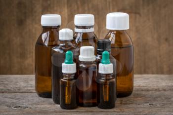 Small bottles with medicinal solution or essential oil on wooden background