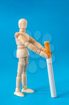 Wooden dool holding a cigarette. Concept of unhealthy habits.