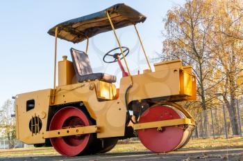 Small road roller standing at parking on autumn season