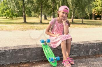 Lovely girl with a penny board in the city park