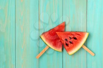 Watermelon slice popsicles on a blue wood background