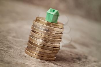 Property Investment or House Mortgage Concept. Green Mini House On Top Of Coin Stack