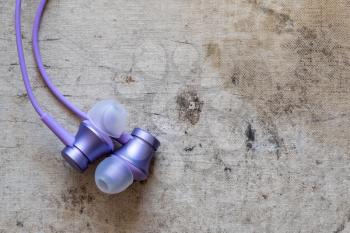 Purple earphones on old canvas background, copy space